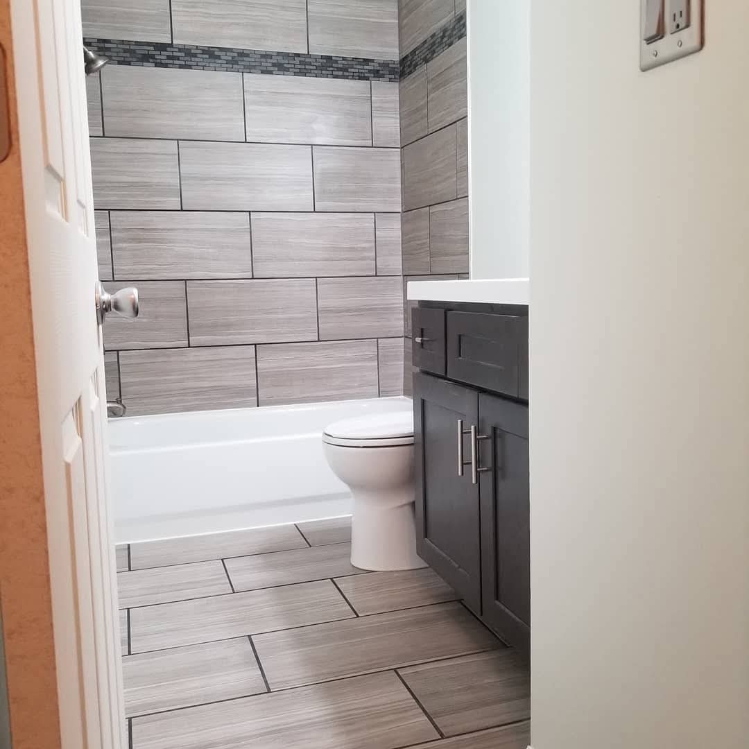 Bathroom after remodel, new gray tile tub surround and vanity