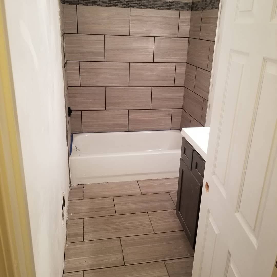 Finished tile bathroom with tub and dark vanity