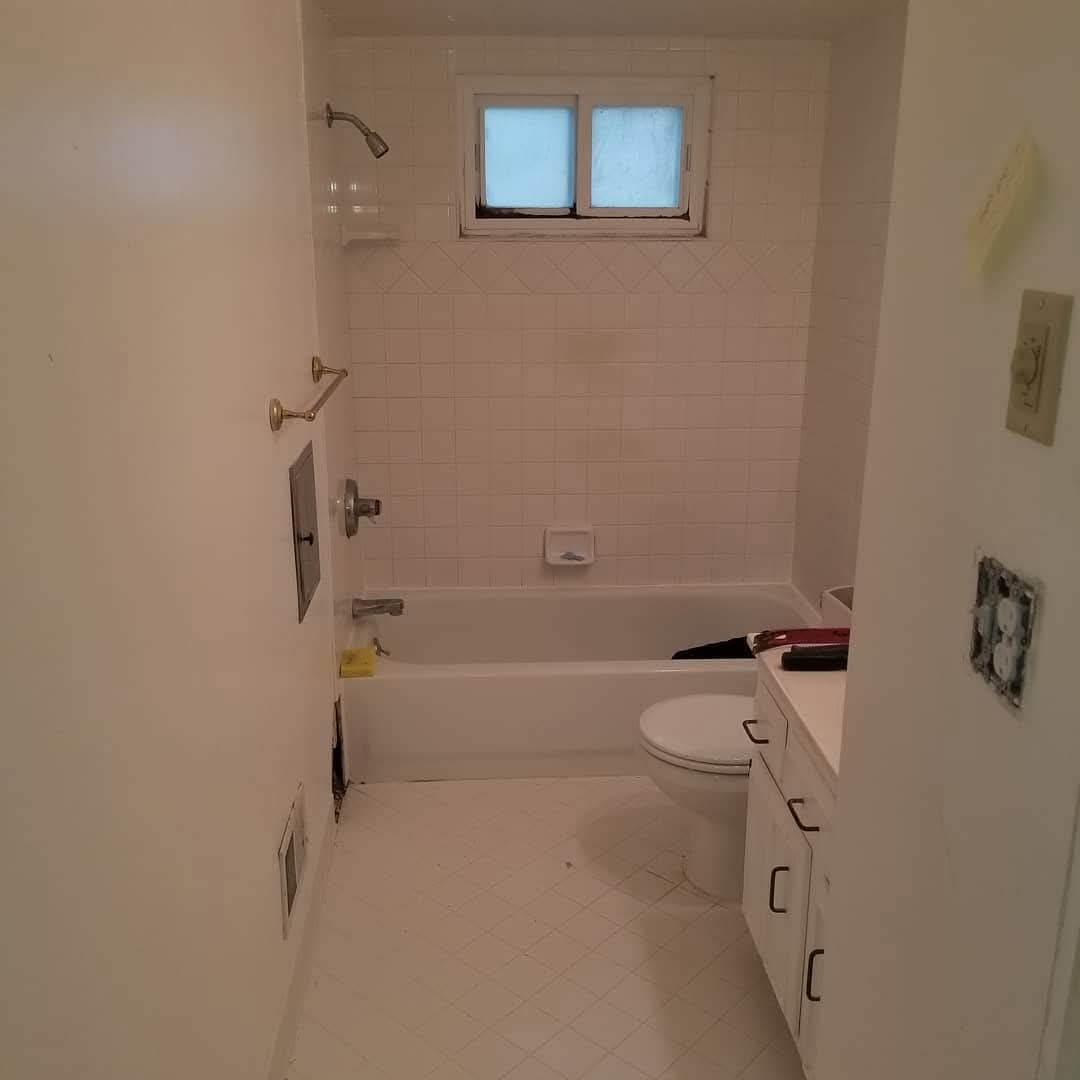 Bathroom before remodel, dated white tile tub surround