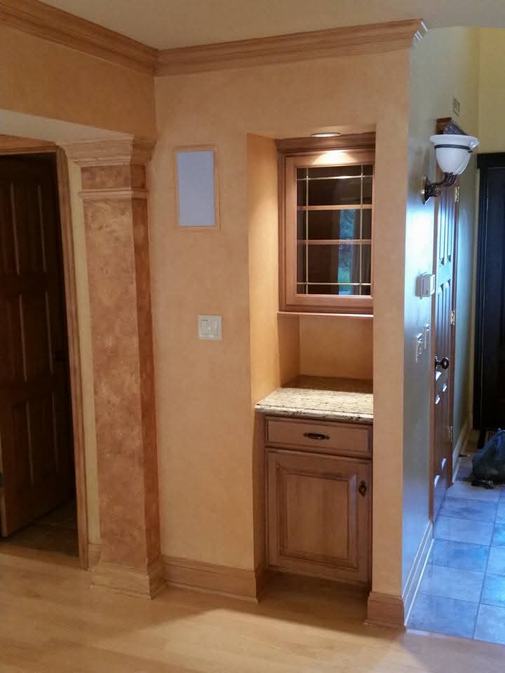 Built-in wet bar nook with leaded glass window and granite counter