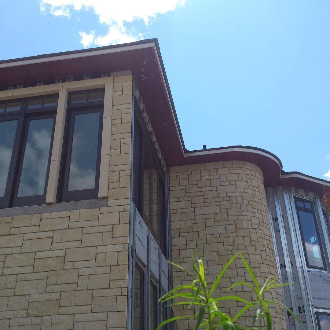 Stone exterior with curved mahogany soffit on new construction