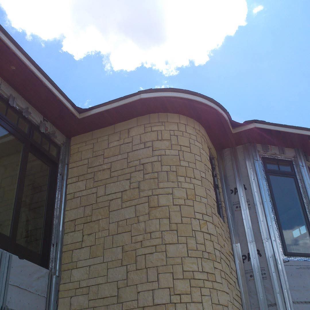 Curved roofline and stone exterior on new construction