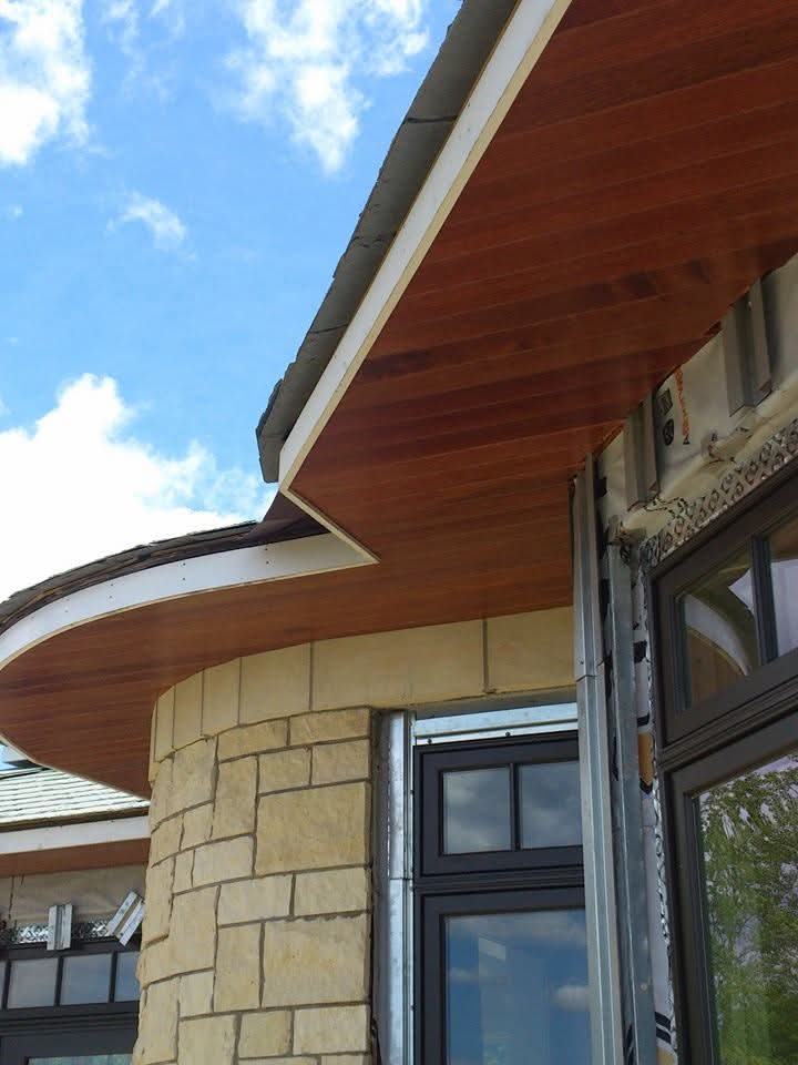 Curved mahogany soffit over stone window surround on new construction